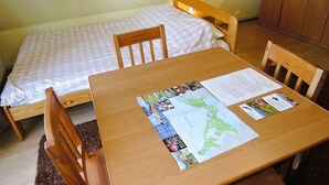 Ein kleines, ordentliches Zimmer mit einem Einzelbett, einem Holztisch mit einer Karte und einem Stuhl.