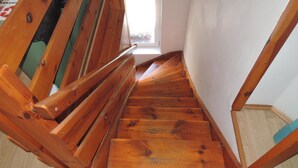 Eine Holztreppe mit Handlauf, die zu einem Fenster mit Blick auf Grünanlagen führt.