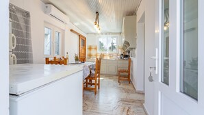 A kitchen with a marble floor, wooden chairs, a white countertop, and a window with curtains. - Apartment 'Ambelaki' with Sea View, Private Garden and Wi-Fi (Antípaxos)