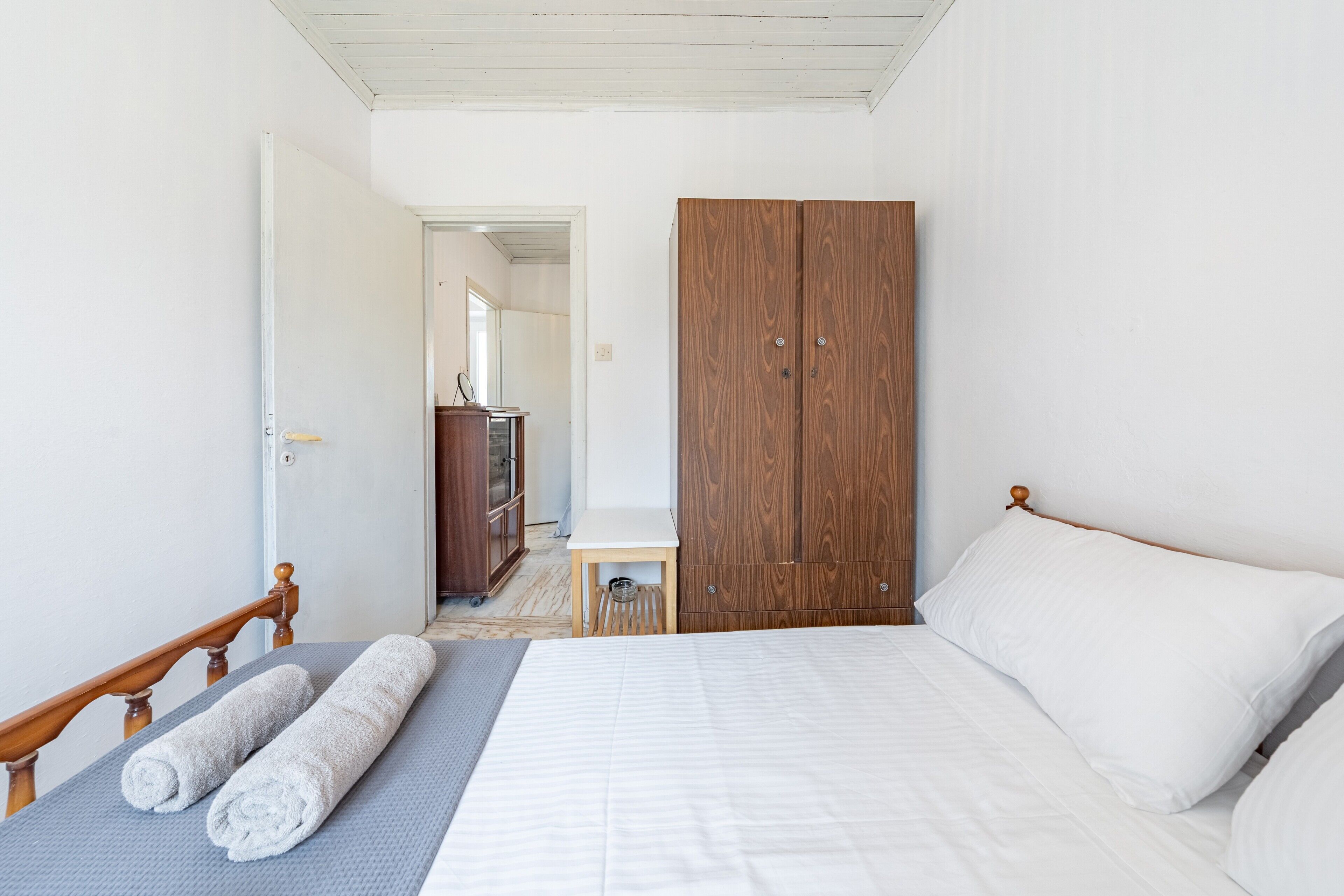 Une chambre à coucher avec un lit, une armoire en bois, une petite table et un miroir.