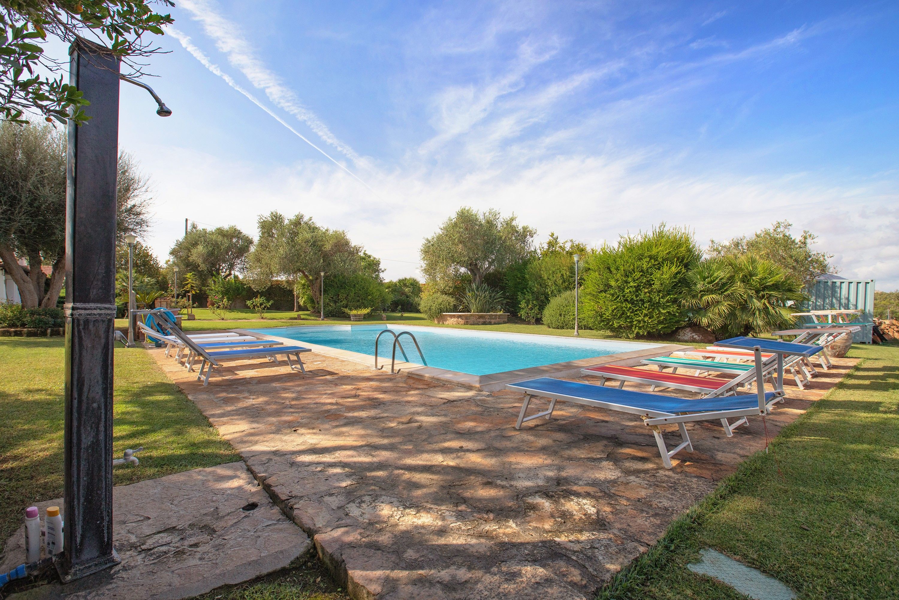A swimming pool with lounge chairs and a stone deck.