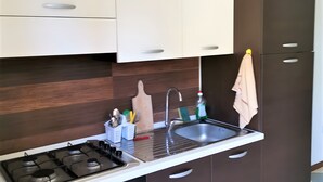 A modern kitchen with a gas stove, oven, and a built-in sink. - Studio 'Ulivo' with Shared Pool, Wi-Fi and Air Conditioning (Alghero)