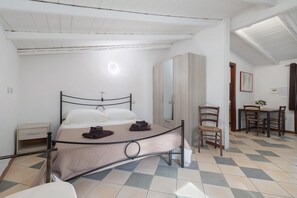 A bedroom with a bed, a chair, a table, and a wardrobe. - Studio 'Ulivo' with shared pool, Wi-Fi and air conditioning (Alghero)