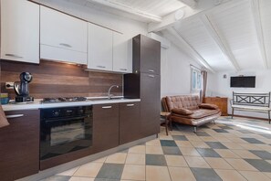 A kitchen with a gas stove, oven, and modern cabinetry. - Studio 'Ulivo' with shared pool, Wi-Fi and air conditioning (Alghero)