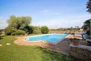 A rectangular swimming pool with a stone border, surrounded by a well-maintained lawn and various shrubs. - Studio 'Ulivo' with shared pool, Wi-Fi and air conditioning (Alghero)