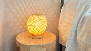 A bedside lamp on a wooden nightstand next to a bed with a metal headboard.
