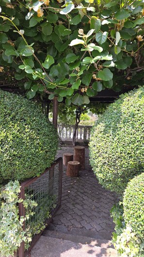 Un sendero en un jardín con setos cuidados, una valla de madera y un farol de piedra.