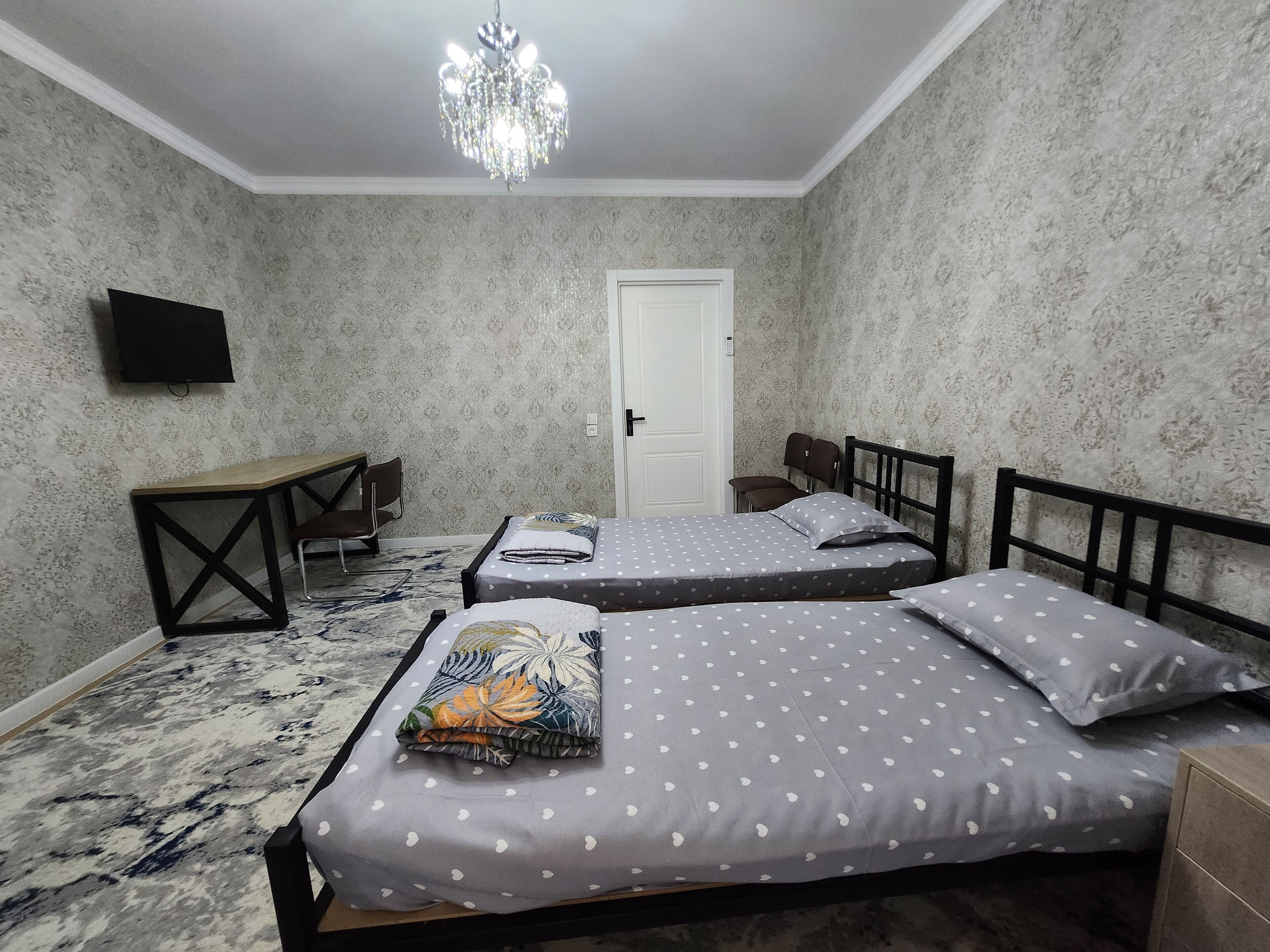 A bedroom with two beds, a desk, and a TV.