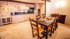 A kitchen with stone walls, wooden cabinets, and a dining table set for breakfast.