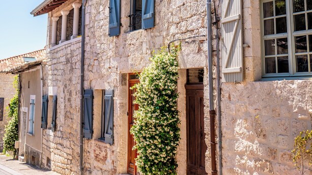 A stone building with shutters, a door, and steps leading to the entrance.