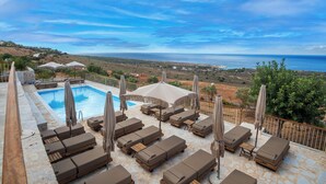 A poolside area with lounge chairs and umbrellas, overlooking a coastal landscape. - Anemos Suites Mani (East Mani)