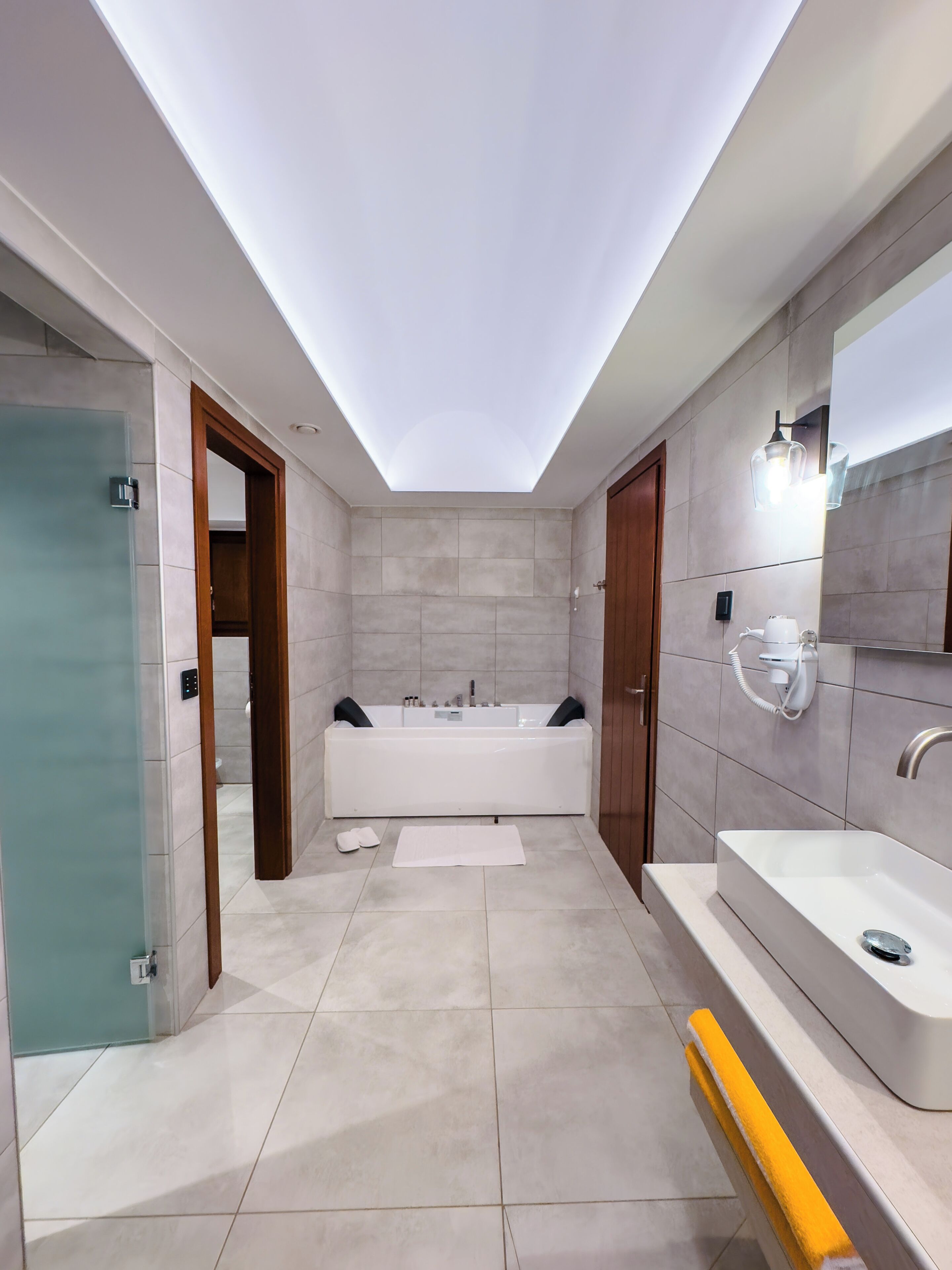 Un baño moderno con tragaluz, una bañera, un lavamanos grande y un espejo.