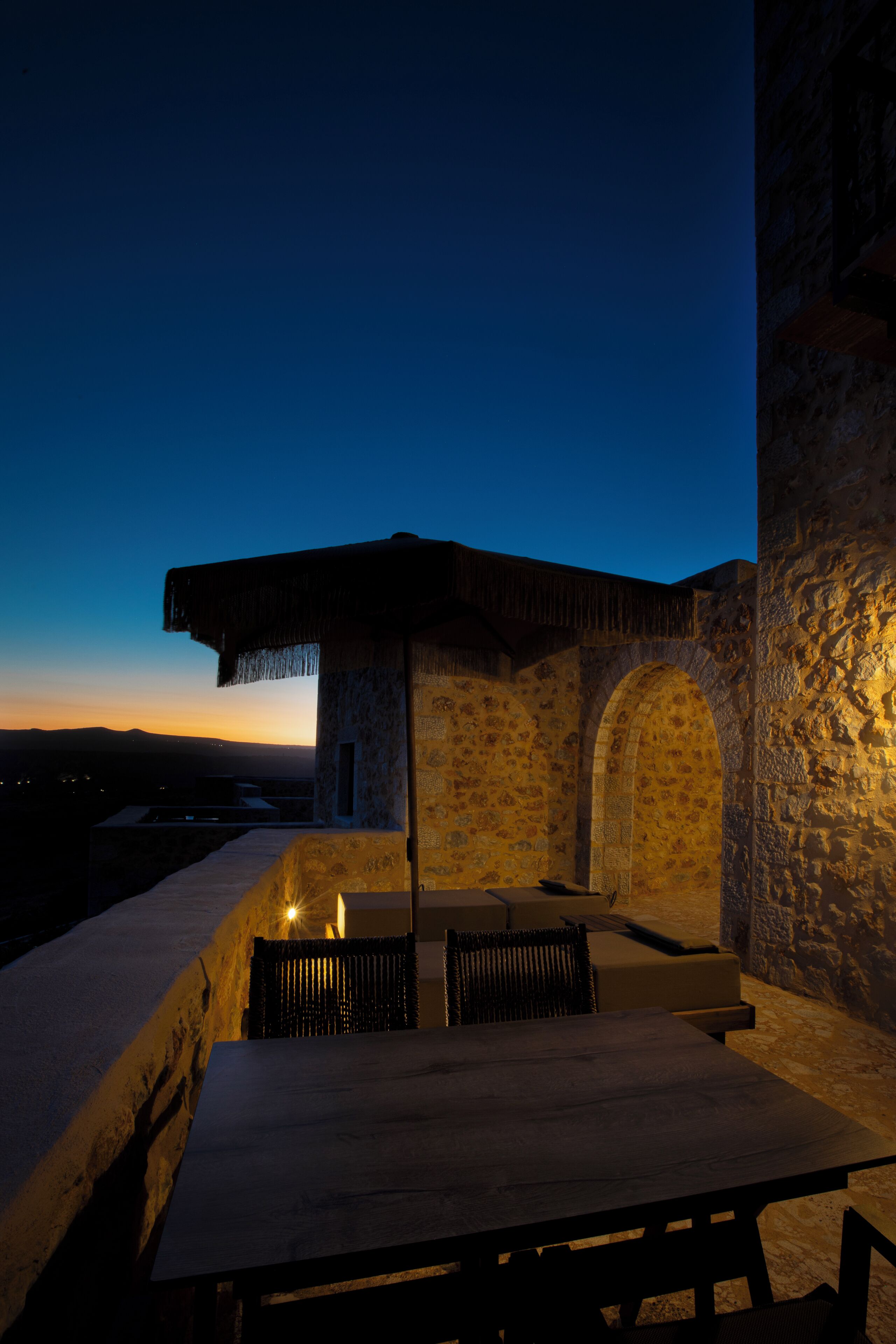 An outdoor patio with stone walls, a table, and chairs.