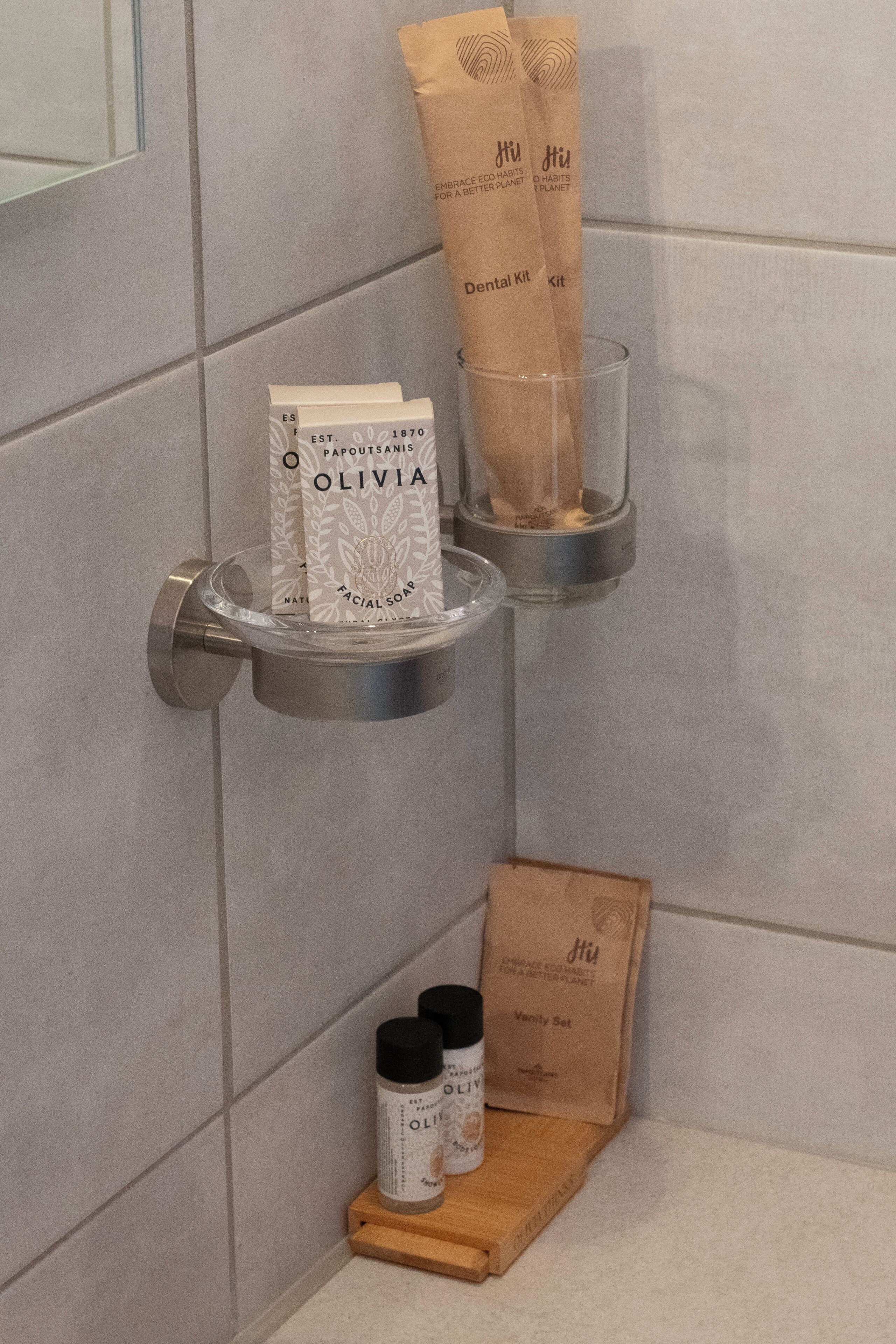 A bathroom with a hand soap dispenser, a toothbrush holder, and a vanity set on a wooden tray.