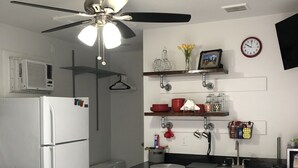 A compact kitchen with a refrigerator, microwave, and a ceiling fan. There is a sink with a faucet, a stool, and a clock on the wall. - Cozy, centralized Studio in wonderful Houston with WiFi, AC (Houston)