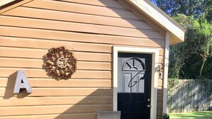 A wooden shed with a black door, a letter 'A' sign, and a decorative metal piece on the wall. - Cozy, centralized Studio in wonderful Houston with WiFi, AC (Houston)