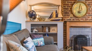 Un salón acogedor con chimenea, un globo terráqueo y una decoración náutica de un velero.