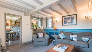 Una sala de estar con una pared azul de acento, una mesa de centro de madera y un sofá gris con almohadones decorativos.