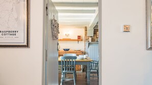 Un comedor con una mesa de madera y sillas azules, un mapa en la pared y una cocina al fondo.