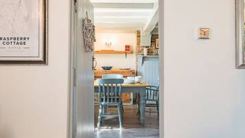 A dining area with a wooden table and blue chairs, a map on the wall, and a kitchen in the background.
