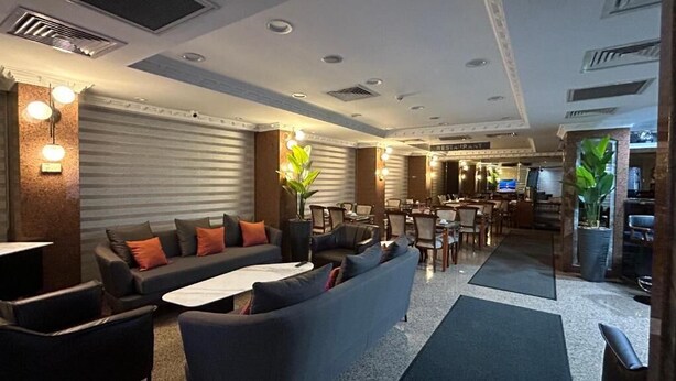 Un hall de hotel con un conjunto de sofás, comedor y una recepción.