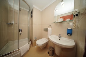 A bathroom with a glass-enclosed shower, a toilet, a sink, and a mirror.