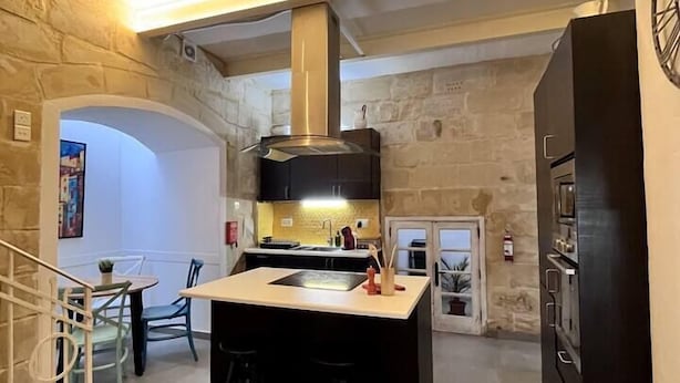 Una cocina compacta con una isla central, una estufa negra y un muro de piedra.