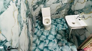 Un baño con inodoro y lavamanos, ambos con diseños de pared que imitan al mármol.