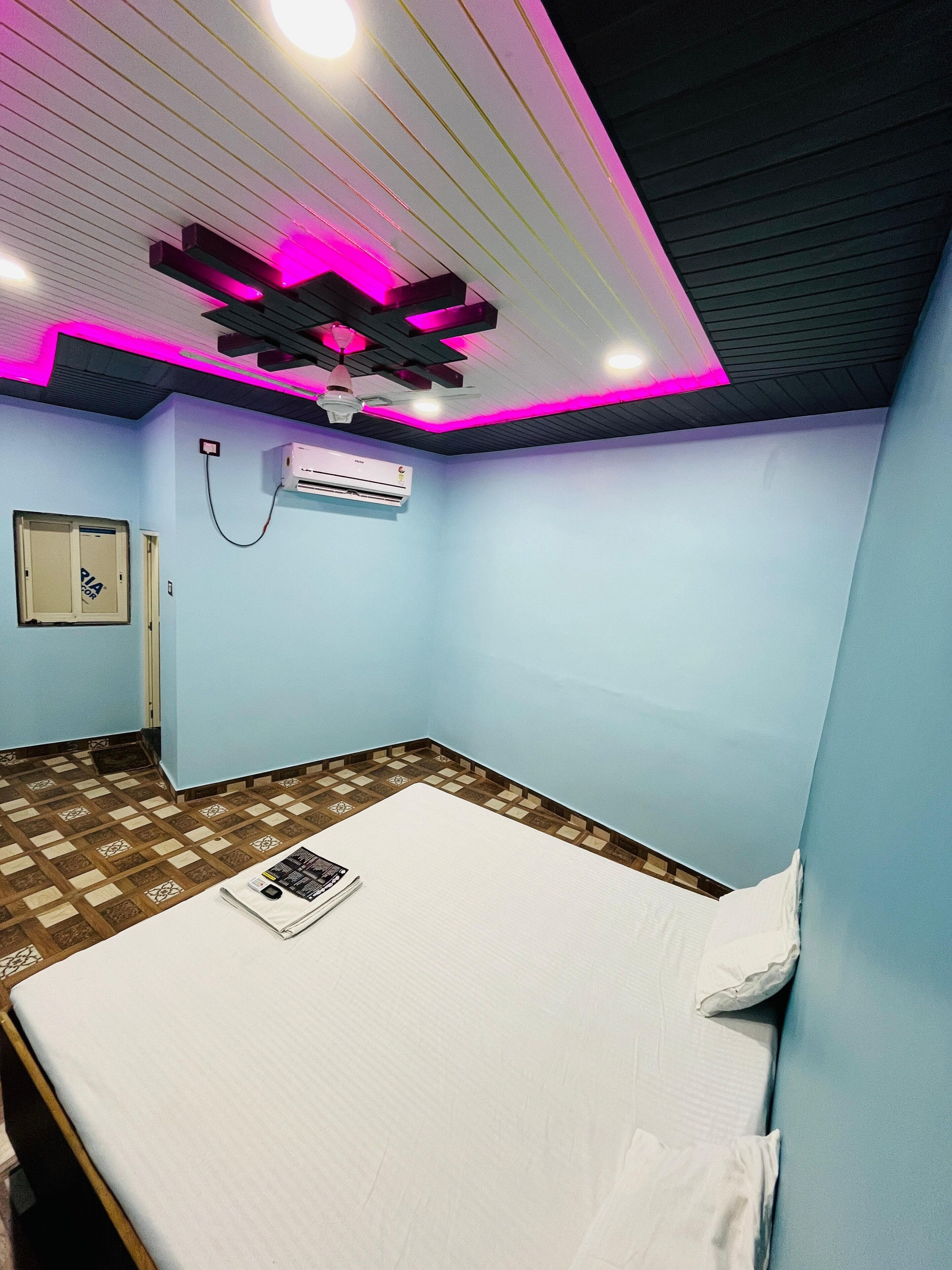 A room with a bed, an air conditioning unit, a window, and a ceiling fan.