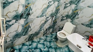Un baño con pared y suelo de mármol, inodoro y lavabo.