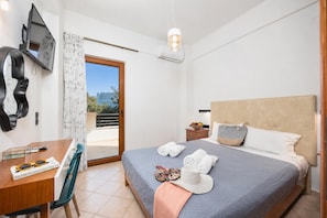 A hotel room with a bed, a desk, a chair, a TV, and a view of the outside.