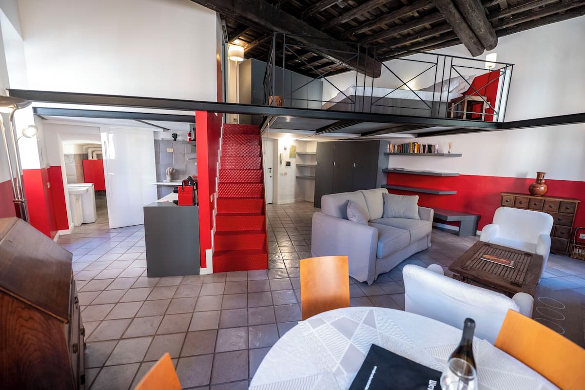 Amplio espacio tipo loft con techo alto, escalera y balcón.
