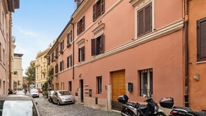 Un carrer empedrat i estret flanquejat per edificis històrics, cotxes aparcats i una motocicleta.