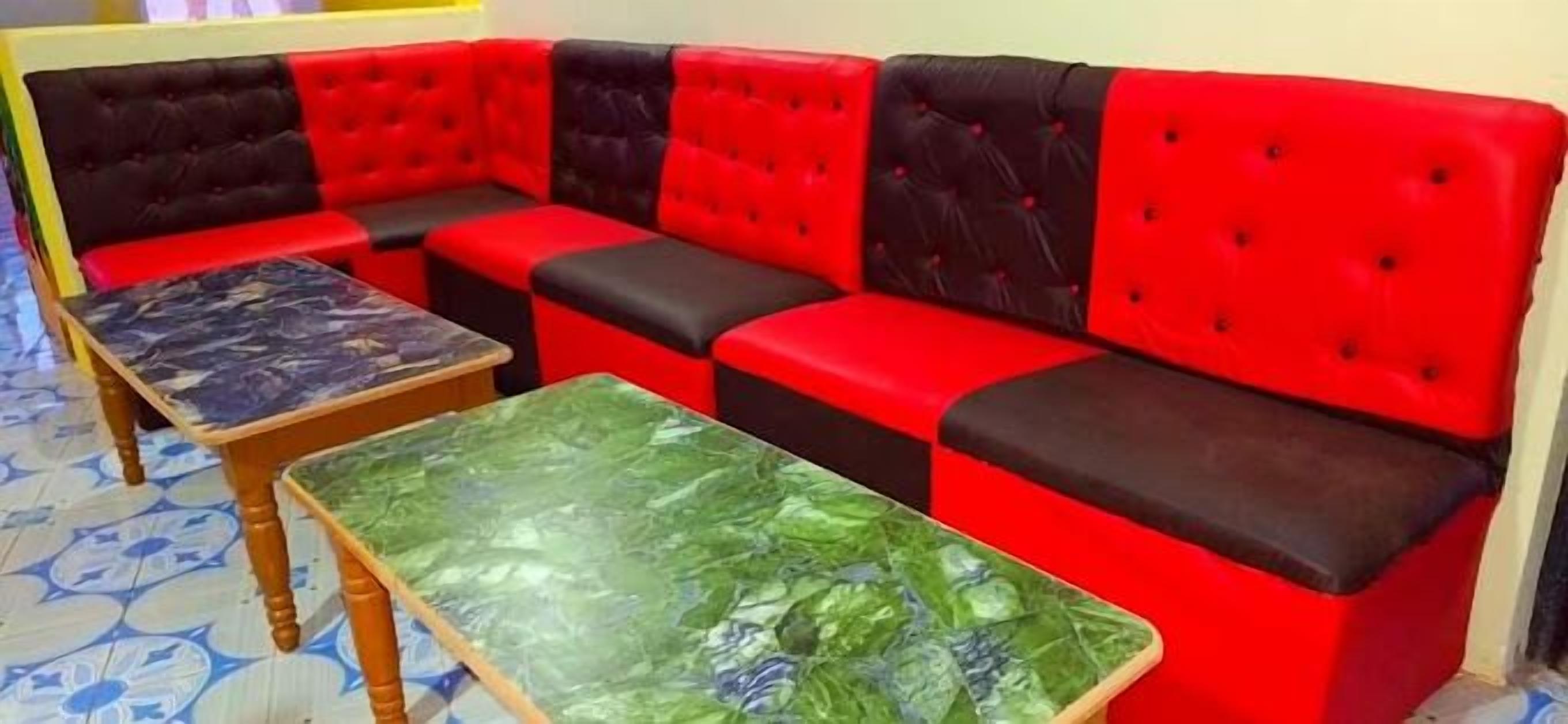 A red and black sectional sofa with a green marble table in front.
