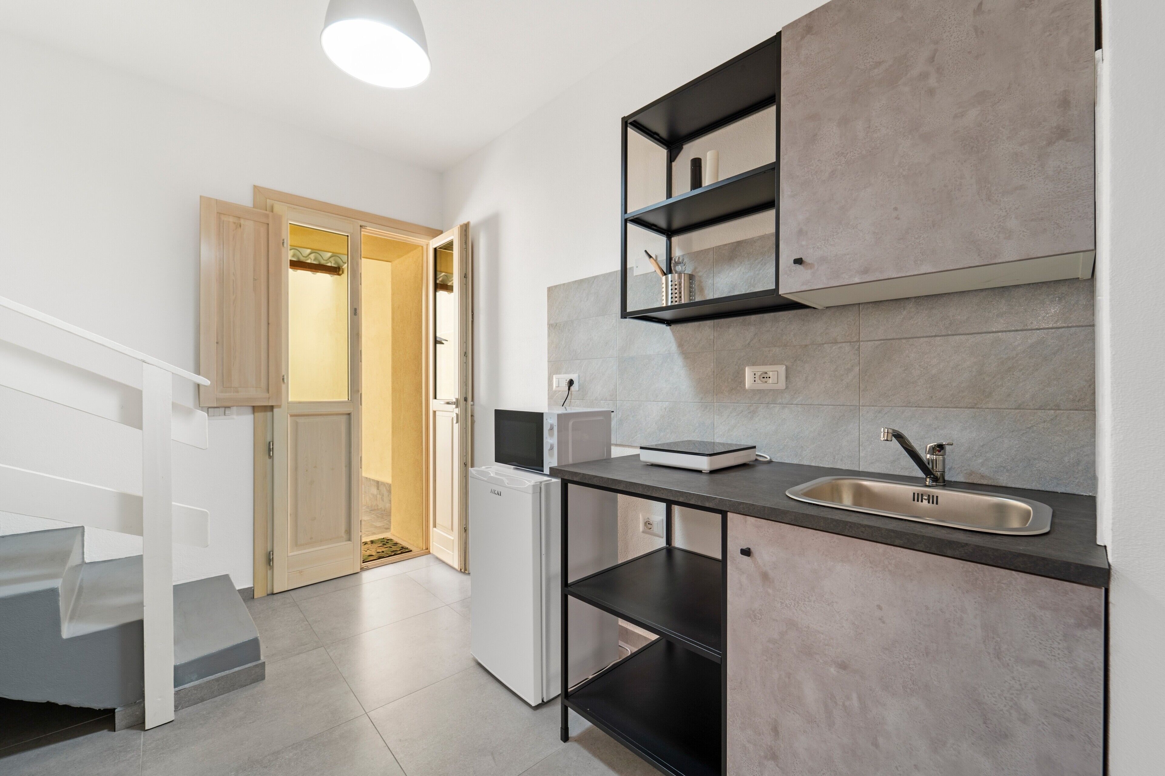 Una cocina moderna con microondas integrado, un lavamanos y una puerta de madera que da a otra habitación.