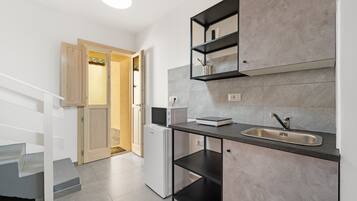 Una cocina moderna con microondas integrado, un lavamanos y una puerta de madera que da a otra habitación.