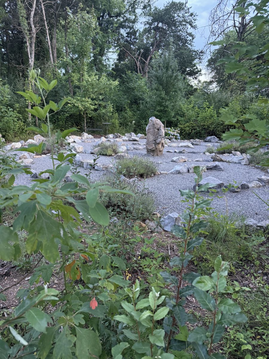 A natural outdoor area with a large rock formation surrounded by gravel and greenery.