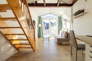 A loft-style bedroom with a wooden staircase, a sofa, a desk, and a view through a glass door. - Charming little house in the heart of the Magni neighborhood—elegant, central, and cozy (Braunschweig)