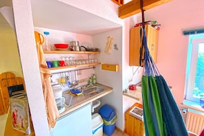 Pieni, käytännöllinen keittiö, jossa on pesuallas, hyllyjä ja ikkuna.