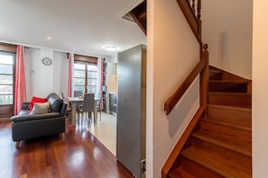 A living area with a sofa, dining table, and chairs, a staircase, and a view of the outdoors. - Spectacular, Very Cozy and Bright Duplex (Cartes)