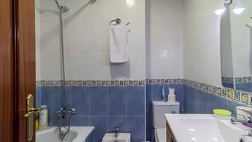 Un baño con bañera, ducha, lavabo, inodoro y espejo.