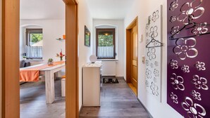 A hallway with a dining area, a refrigerator, and a wall with decorative metal flowers.