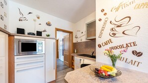 A modern kitchen with a microwave, coffee machine, and a fruit bowl on the counter.