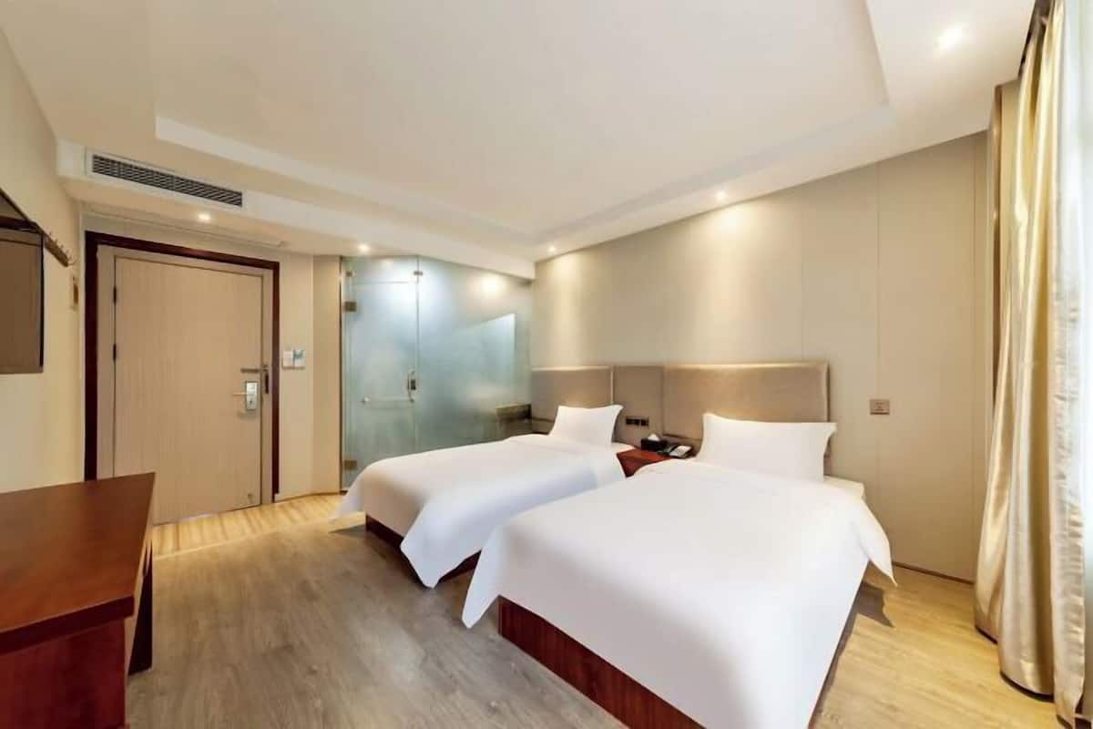 A hotel room with two beds, a desk, and a door.
