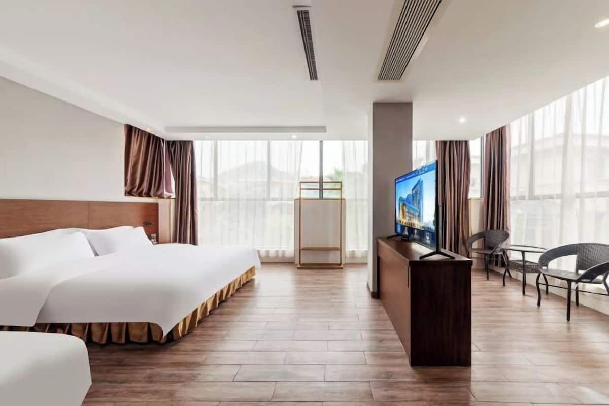 A hotel room with a bed, a TV, a desk, and a chair.