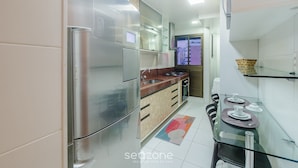 Una cocina moderna con electrodomésticos de acero inoxidable, una mesa de comedor de vidrio y vistas al exterior.