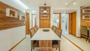 Un comedor moderno con una mesa larga, paneles de madera y estanterías empotradas.
