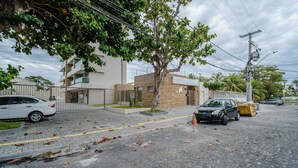 Zona residencial con un edificio moderno, un árbol y coches aparcados.