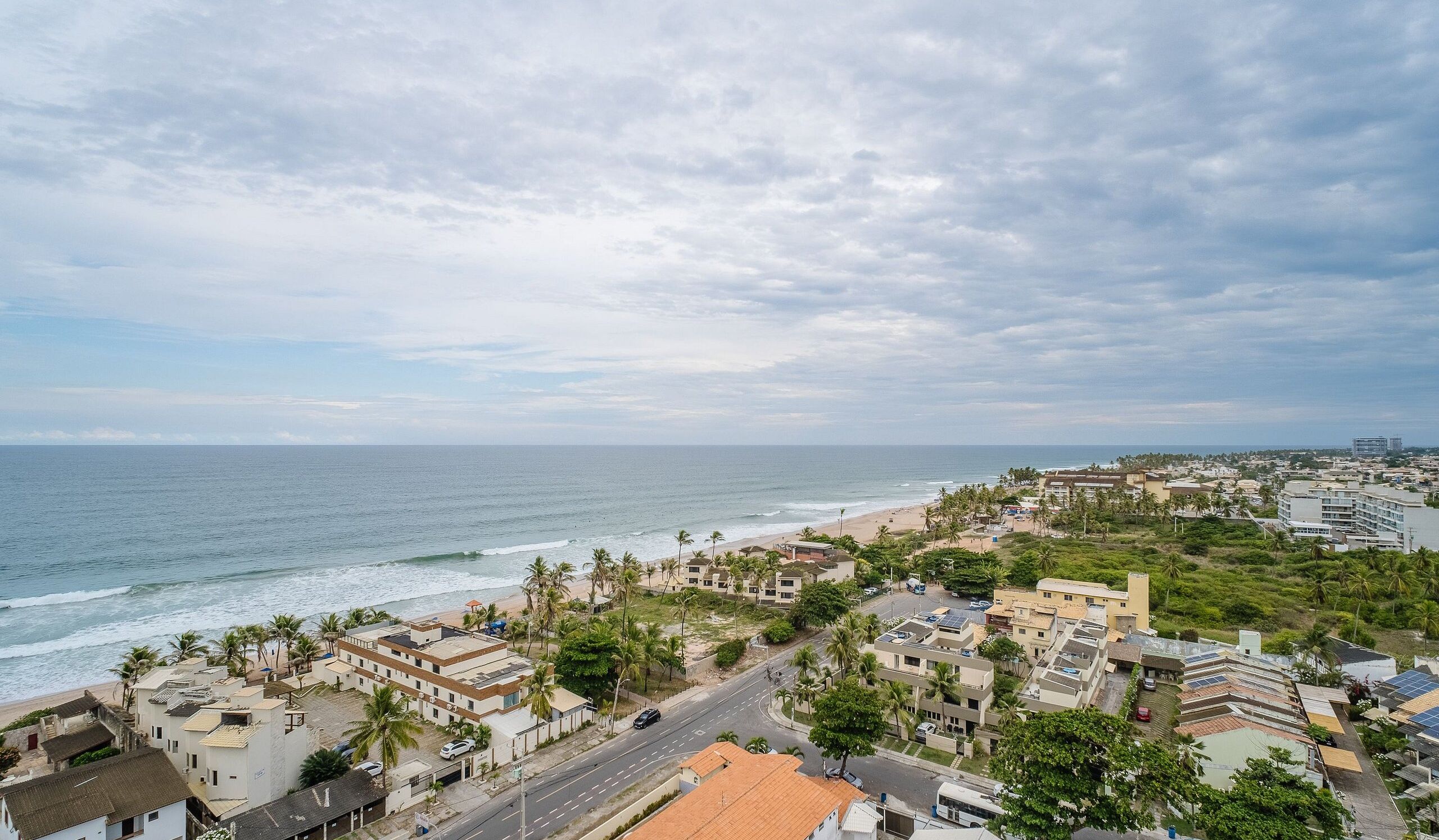 Une ville côtière avec des bâtiments situés près de la plage, une route et des palmiers.