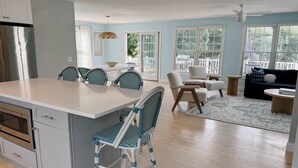 Een moderne keuken met een groot eiland, een eethoek met stoelen, een bank en een plafondventilator.
